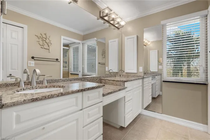 Full bath featuring double vanity, crown molding, and light tile patterned floors