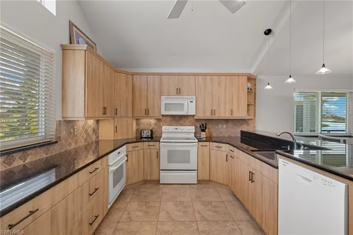 Kitchen featuring white appliances, decorative light fixtures, backsplash, open shelves, and light tile patterned flooring