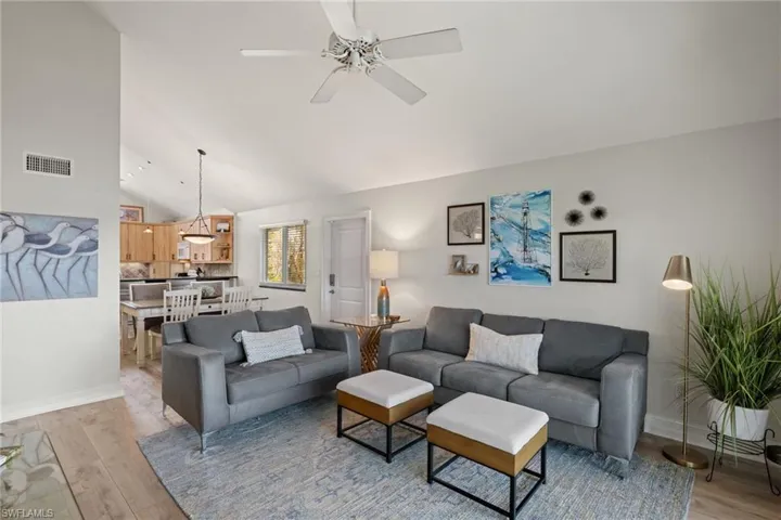 Living room with light wood finished floors, ceiling fan, and high vaulted ceiling