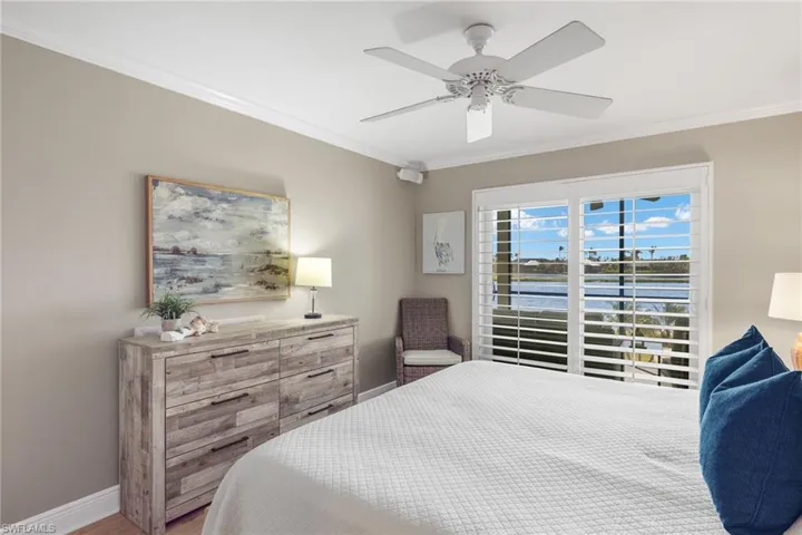 Bedroom featuring ornamental molding, a water view, a ceiling fan, and wood finished floors