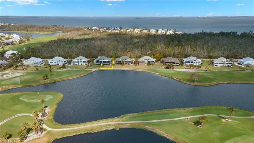 View of property location with a nearby body of water, a golf course, and nearby suburban area