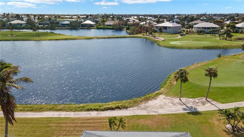 Aerial view of residential area featuring a golf course and a large body of water