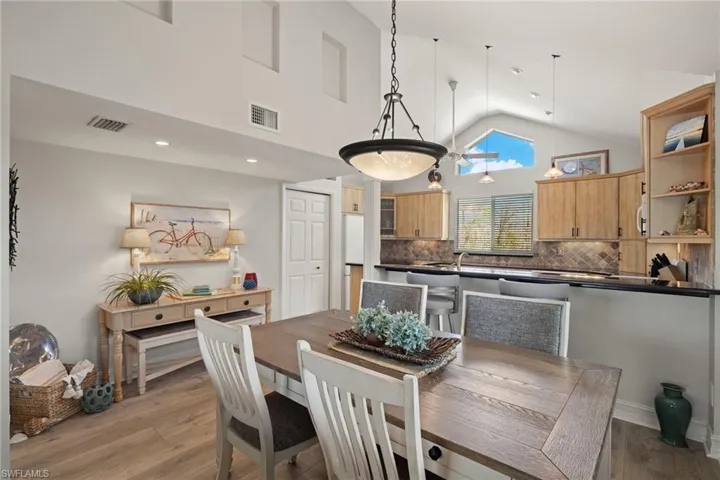 Dining room with high vaulted ceiling and light wood finished floors