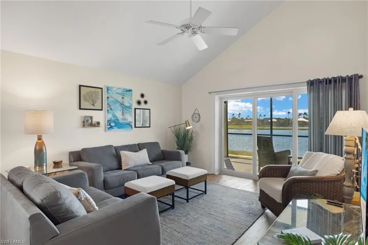 Living room featuring high vaulted ceiling, a water view, wood finished floors, and ceiling fan