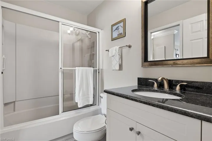 Full bath with vanity and combined bath / shower with glass door