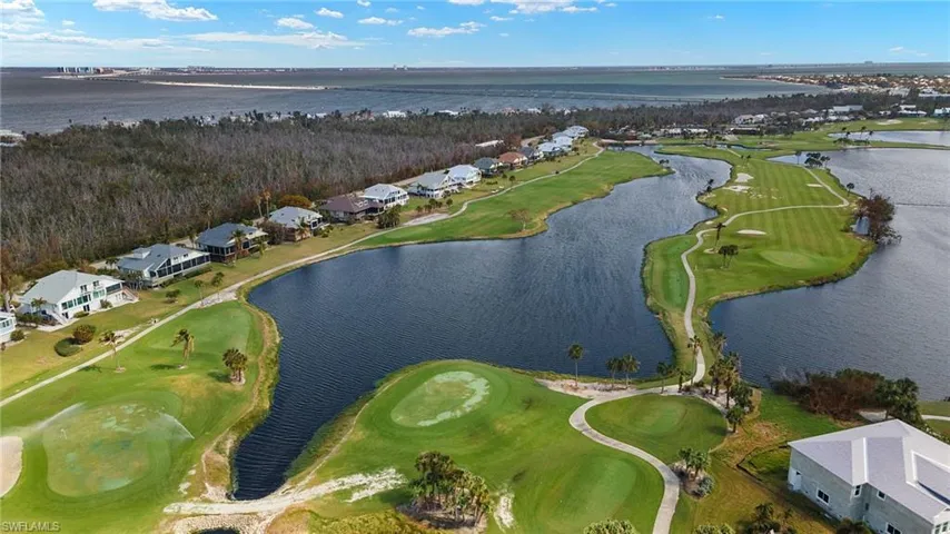Aerial view of property and surrounding area featuring a golf club, nearby suburban area, and a nearby body of water