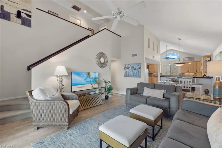 Living area with high vaulted ceiling, light wood-style floors, and a ceiling fan