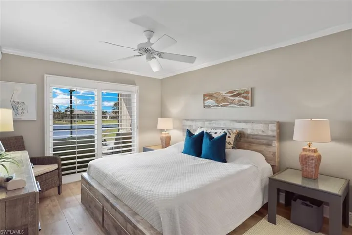 Bedroom featuring crown molding, wood finished floors, a water view, and a ceiling fan