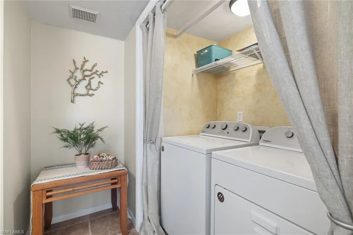 Washroom with washing machine and clothes dryer and tile patterned flooring