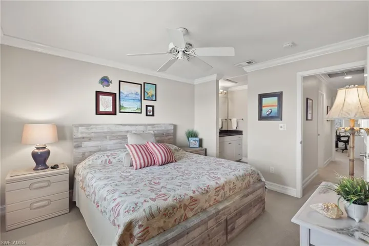 Bedroom featuring light colored carpet, crown molding, ceiling fan, and ensuite bathroom