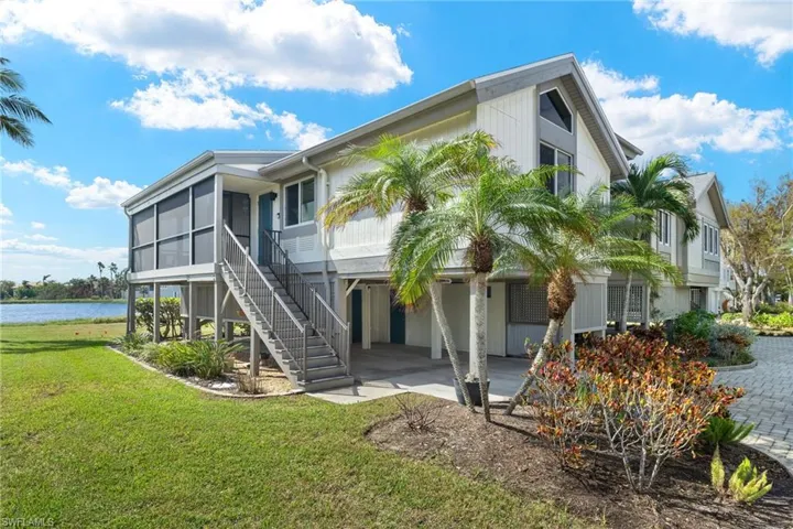 Back of property with a water view, a patio, a yard, a sunroom, and stairs