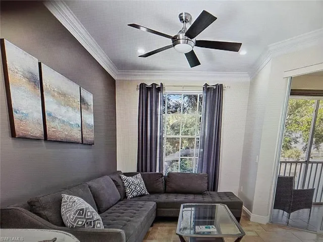 Living room with a ceiling fan, crown molding, and wallpapered walls