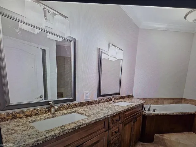 Bathroom with double vanity, a garden tub, and ornamental molding