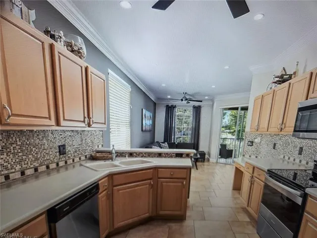 Kitchen with backsplash, a ceiling fan, stainless steel appliances, a peninsula, and light countertops