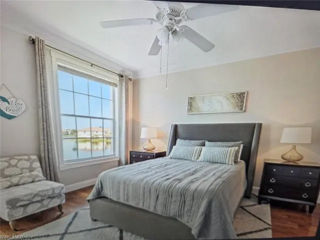 Bedroom with wood finished floors, a water view, and ceiling fan