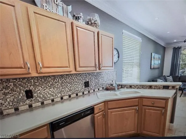 Kitchen featuring a peninsula, open floor plan, stainless steel dishwasher, light countertops, and decorative backsplash