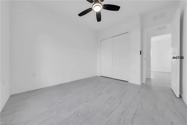 Unfurnished bedroom with ceiling fan and a closet