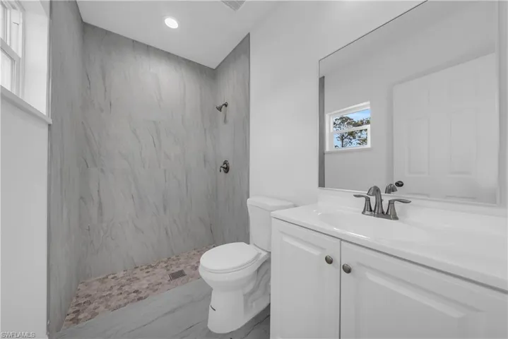 Full bathroom featuring a marble finish shower and vanity