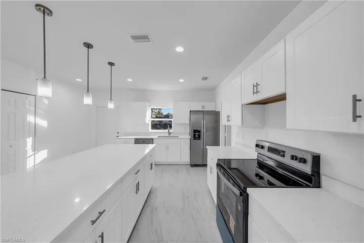 Kitchen with stainless steel appliances, white cabinetry, pendant lighting, light stone counters, and recessed lighting