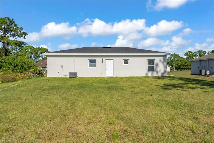 Back of property featuring a lawn and stucco siding