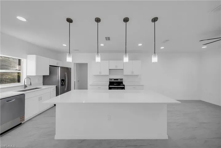 Kitchen featuring appliances with stainless steel finishes, pendant lighting, a kitchen island, white cabinets, and recessed lighting