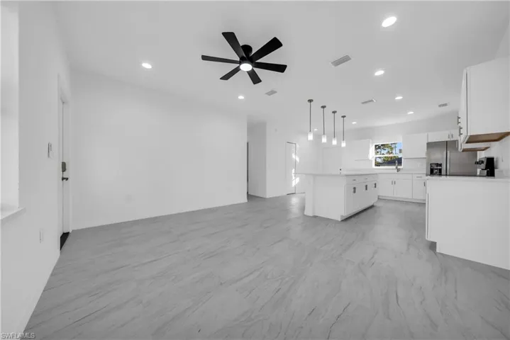 Kitchen featuring white cabinets, light countertops, open floor plan, hanging light fixtures, and recessed lighting