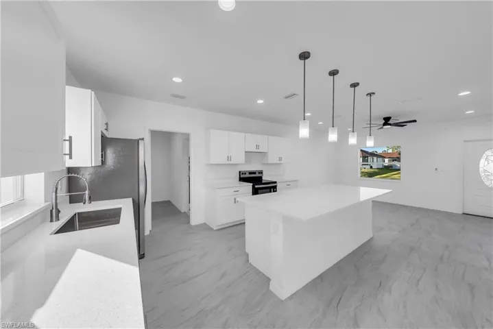 Kitchen with hanging light fixtures, appliances with stainless steel finishes, healthy amount of natural light, white cabinets, and recessed lighting