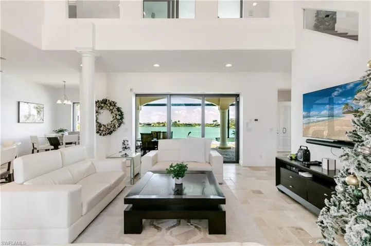 Living area featuring recessed lighting, a high ceiling, and light stone finish flooring