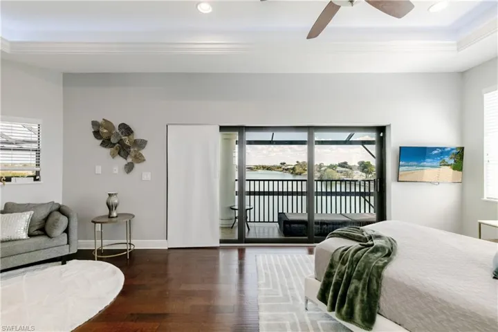 Bedroom featuring dark wood-style flooring, access to outside, a ceiling fan, recessed lighting, and a tray ceiling