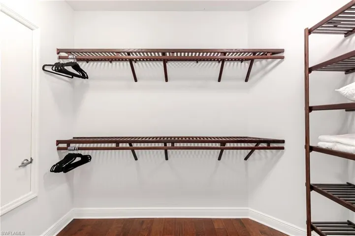 Walk in closet with dark wood-type flooring
