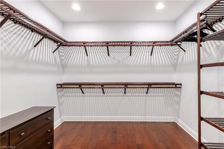 Walk in closet with dark wood-style floors