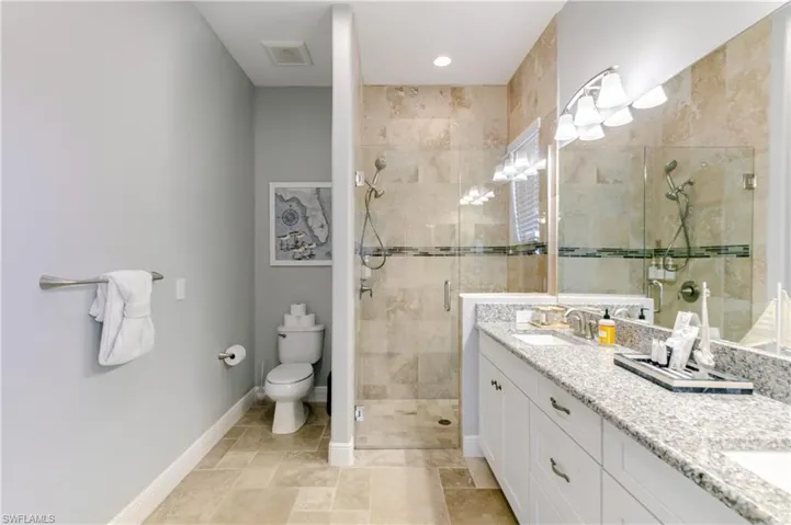 Full bathroom featuring double vanity and a shower stall