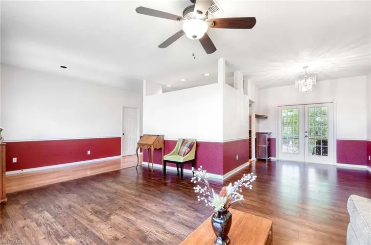 Living area with baseboards, wood finished floors, a chandelier, a ceiling fan, and french doors
