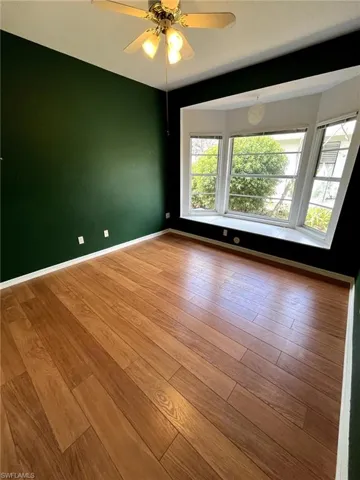 Spare room featuring wood finished floors, a ceiling fan, and baseboards