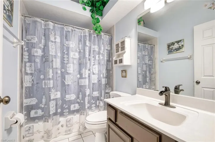 Bathroom featuring toilet, tile patterned floors, a shower with curtain, and vanity