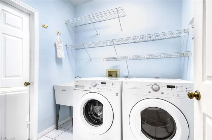 Washroom featuring washing machine and clothes dryer and light tile patterned floors