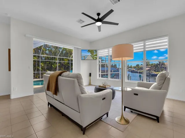 Living room featuring a sunroom, a ceiling fan, a water view, and plenty of natural light