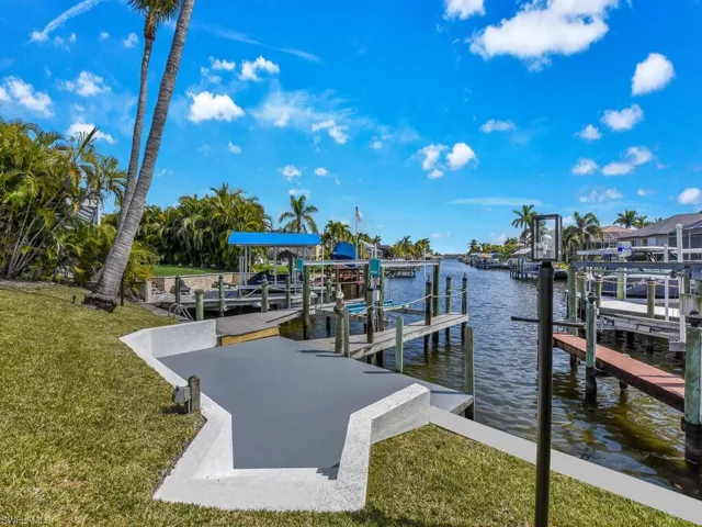 Dock area with a water view, a lawn, and boat lift