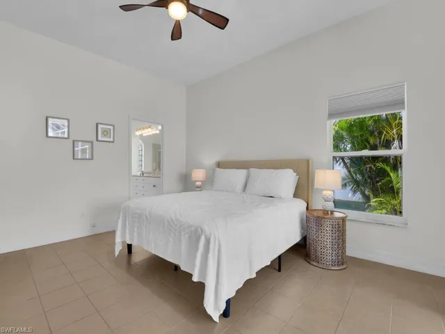 Bedroom with a ceiling fan, connected bathroom, and light tile patterned floors