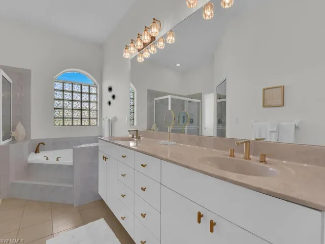 Full bath featuring double vanity, a bath, light tile patterned flooring, and a shower stall