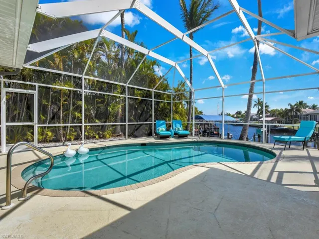 Outdoor pool with boat lift, a boat dock, a sunroom, and a lanai