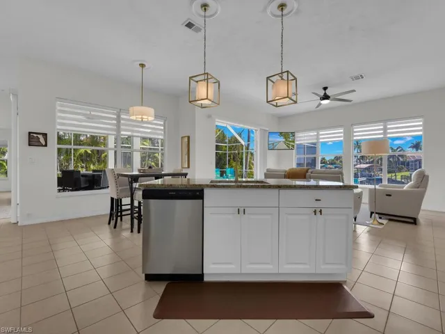 Kitchen with ceiling fan, dishwasher, decorative light fixtures, and dark stone counters