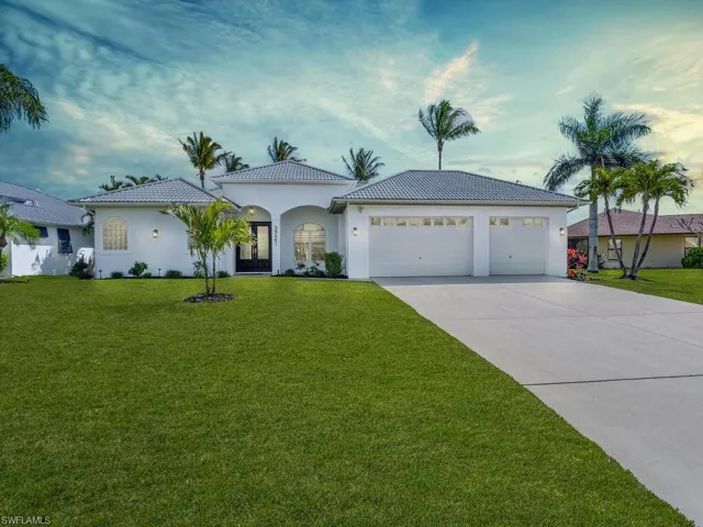View of front of house with an attached garage, a front lawn, driveway, stucco siding, and a tiled roof