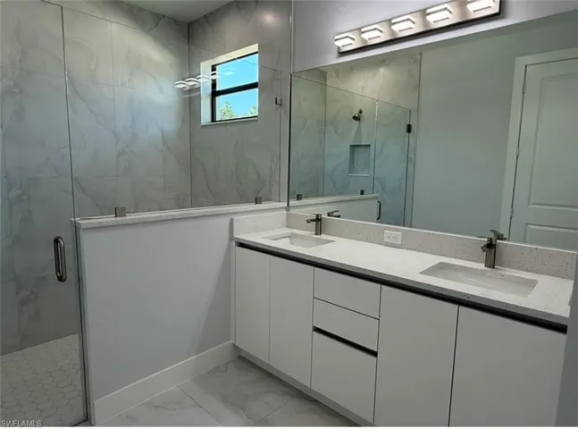 Full bath featuring marble finish floor, a sink, and a shower stall