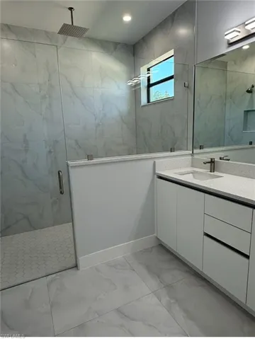 Bathroom featuring recessed lighting, marble finish floor, vanity, and a marble finish shower