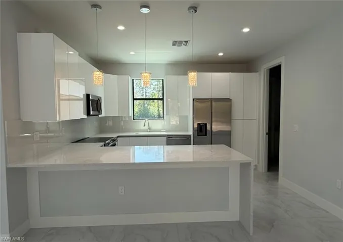 Kitchen with marble finish floor, appliances with stainless steel finishes, backsplash, and a sink