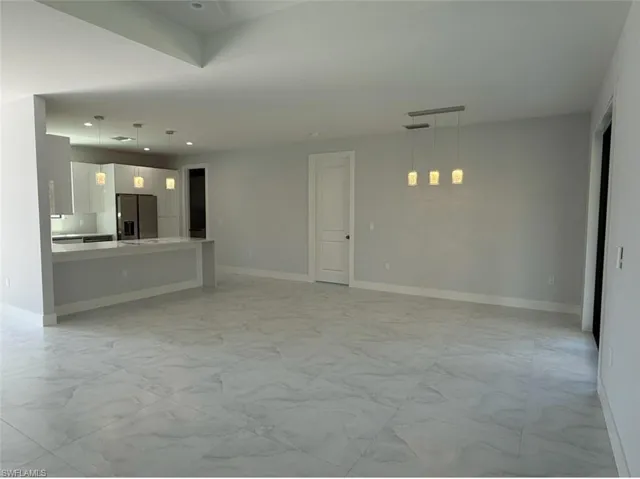 Unfurnished living room with recessed lighting, marble finish floor, and baseboards