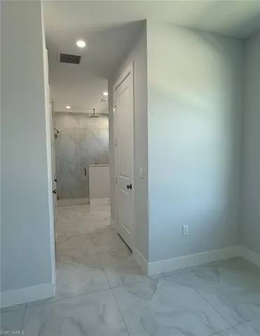 Hall with marble finish floor, visible vents, and baseboards
