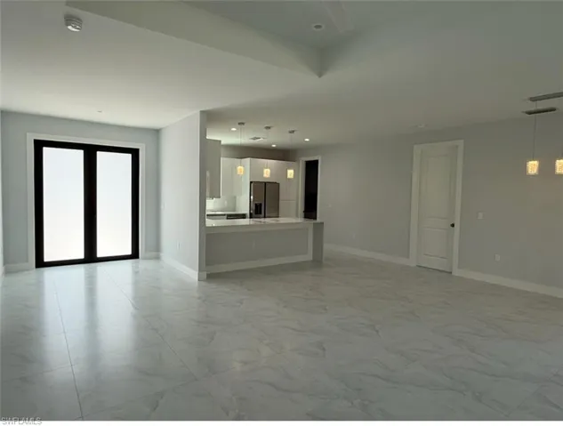 Unfurnished living room with marble finish floor, french doors, recessed lighting, and baseboards