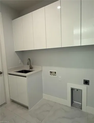 Laundry area featuring cabinet space, marble finish floor, electric dryer hookup, washer hookup, and a sink